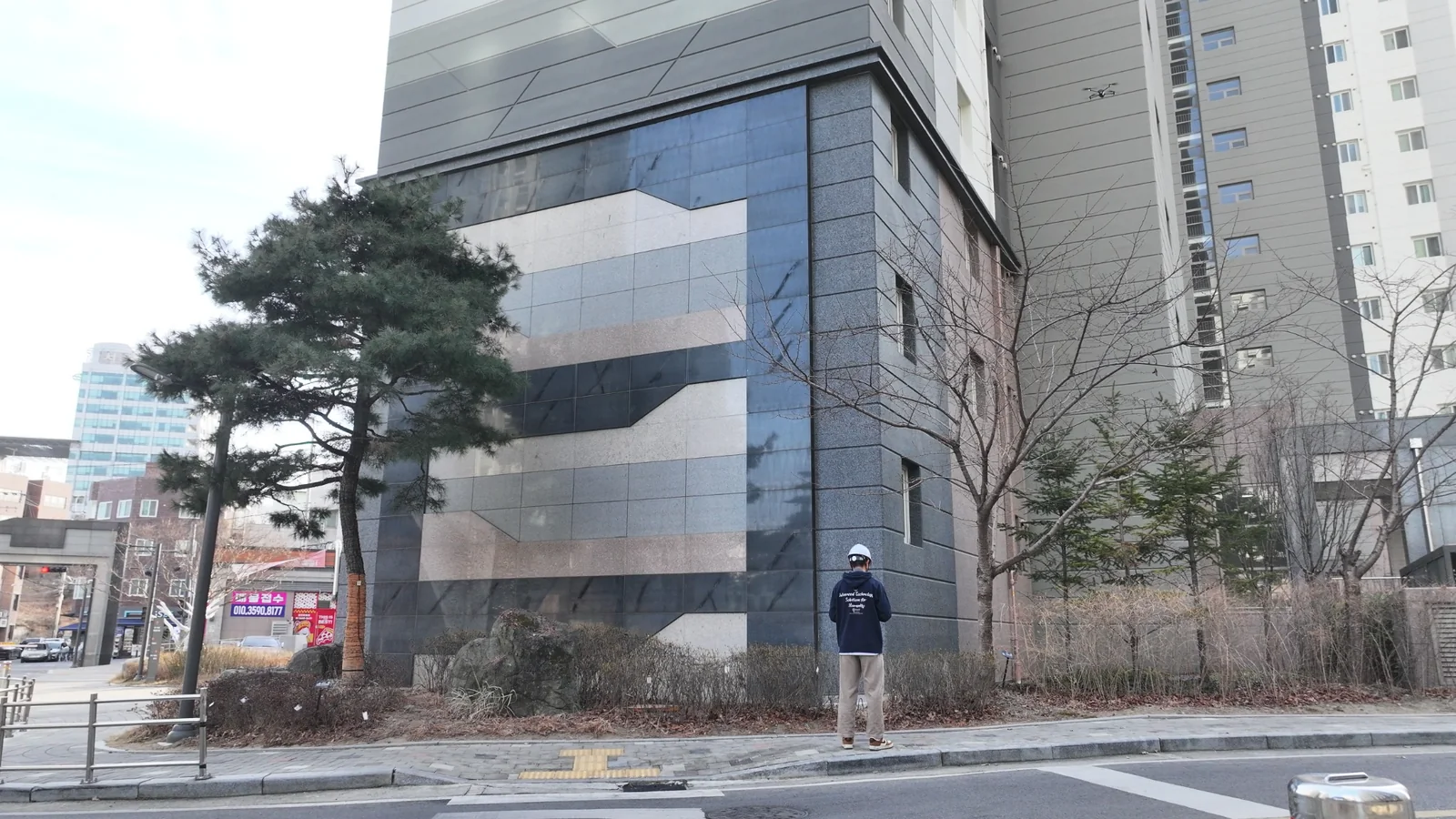 아파트 외벽을 점검하는 드론과 현장 조종자